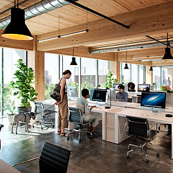 A person standing in front of a desk with people sitting at it.