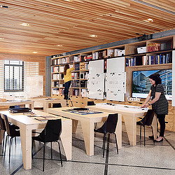 A room with a table and chairs and a shelf with books on it.